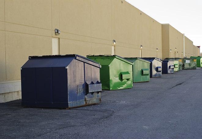 a waste management truck unloading into a construction dumpster in Fort Eustis VA